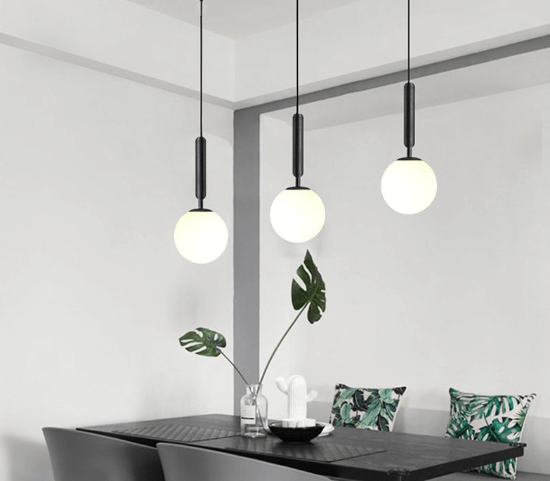 Modern glass ball light fixtures hanging over a dining table.