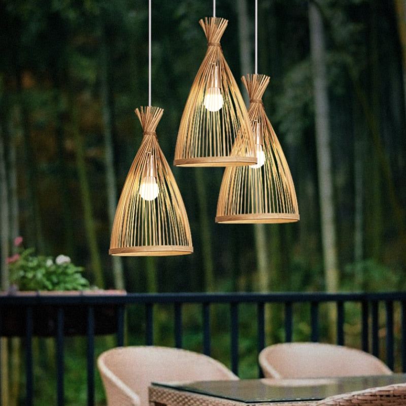 Bamboo pendant lights with rattan design hanging over a table in an outdoor setting.