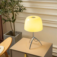 Italian tripod desk lamp with glass shade on minimalist base, ideal for modern interiors.