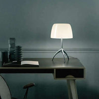 Italian tripod desk lamp with glass shade on minimalist base, ideal for modern interiors.