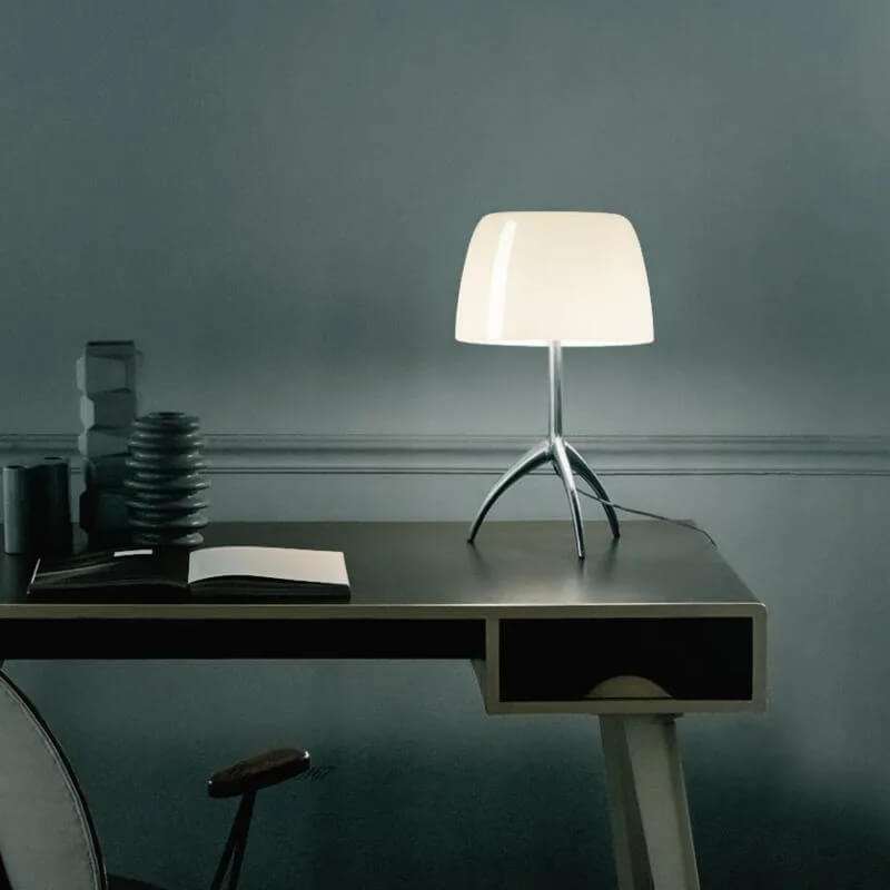 Italian tripod desk lamp with glass shade on minimalist base, ideal for modern interiors.