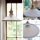 White ceramic brass pendant light fixtures in a Nordic Japanese style, elegantly hanging in a well-decorated room.