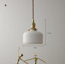 White ceramic brass pendant light fixtures in a Nordic Japanese style, elegantly hanging in a well-decorated room.