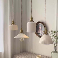 White ceramic brass pendant light fixtures in a Nordic Japanese style, elegantly hanging in a well-decorated room.