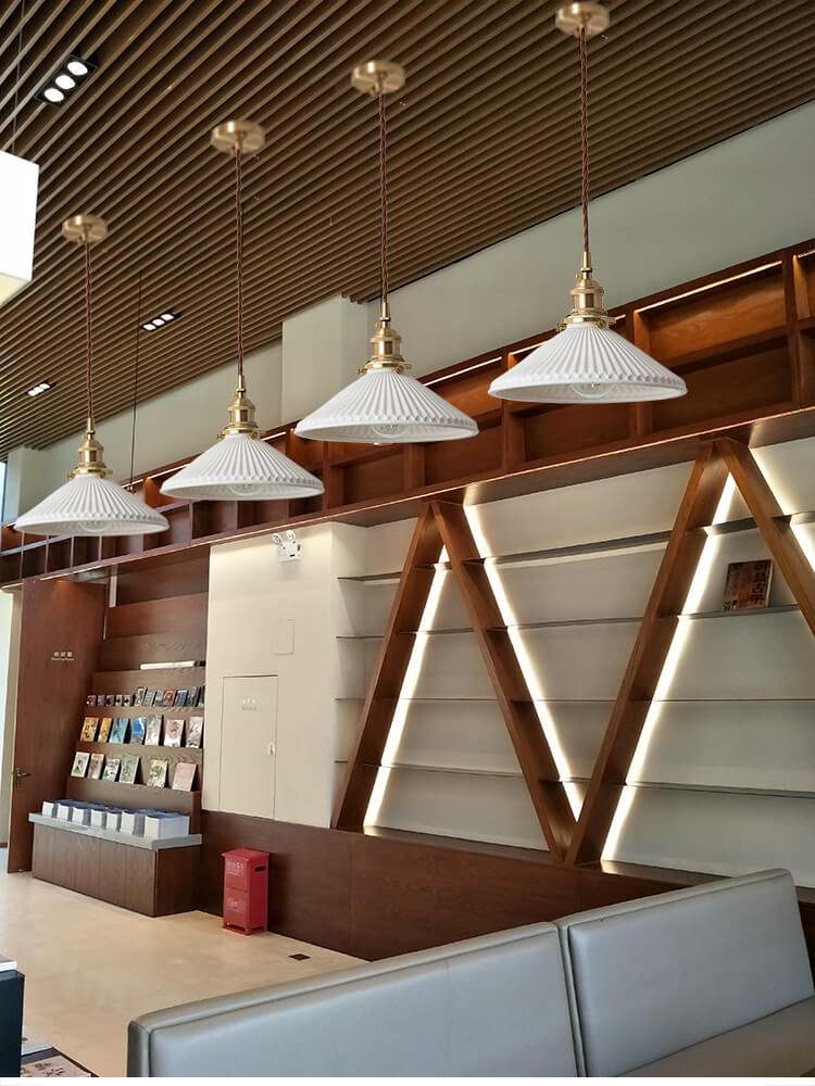 White ceramic pendant lights in Nordic Japanese style with brass accents, hanging above a table.