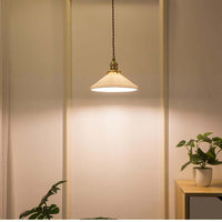 White ceramic pendant lights in Nordic Japanese style with brass accents, hanging above a table.