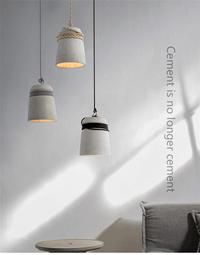 Concrete pendant lights with hemp rope in a modern, minimalist design, hanging above a gray interior setting.