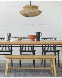 Boho rattan lamp hanging over kitchen island with elegant dining setup.