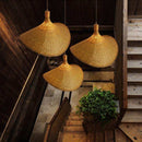 Bamboo straw hat lamp with handmade lampshade hanging indoors, creating warm accent lighting.